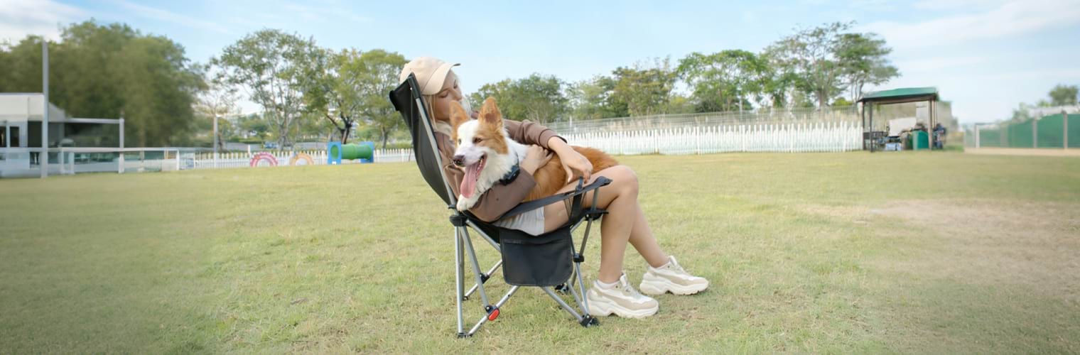 A pet owner relaxing outdoors, hugging her happy dog wearing a Sovelivee training collar.